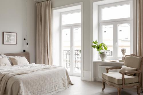 a bedroom with a bed and a chair and windows at Lwowska Studios - STAYINWARSAW in Warsaw