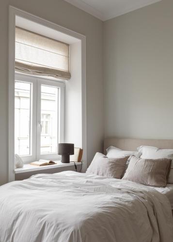 a white bedroom with a large bed and a window at Lwowska Studios - STAYINWARSAW in Warsaw