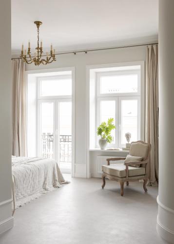 a bedroom with a bed and a chair and windows at Lwowska Studios - STAYINWARSAW in Warsaw