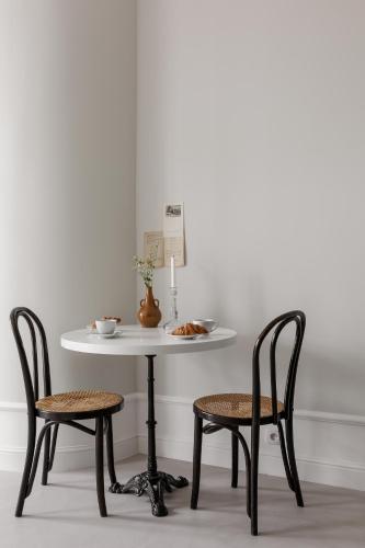 a white table with two chairs and a table with a bowl on it at Lwowska Studios - STAYINWARSAW in Warsaw