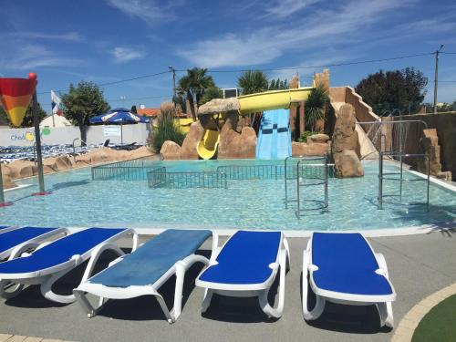 - une piscine avec 2 chaises longues et un toboggan dans l'établissement Richards Holidays, à Jard-sur-Mer