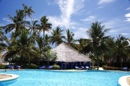 a resort swimming pool with chairs and palm trees at Breezes Beach Club and Spa in Bwejuu