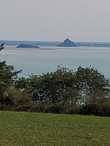 a view of the water with a lighthouse in the distance at Chez Jollyjune, à moins d'une heure du Mont Saint Michel in Champeaux