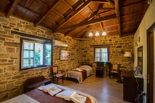 a bedroom with two beds in a stone walled room at Archontiko Riziko in Kambos