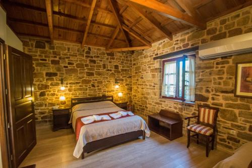 a bedroom with a bed and a stone wall at Archontiko Riziko in Kambos