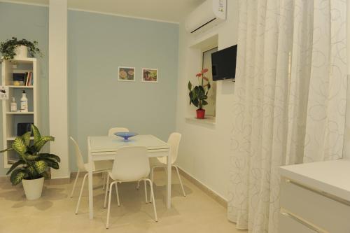 una sala da pranzo bianca con tavolo e sedie di B&B Carpe Diem a Gravina di Catania