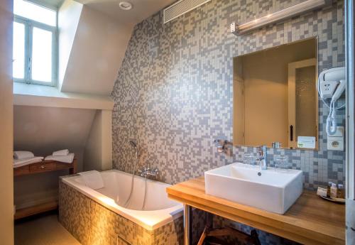 a bathroom with a tub, sink, and mirror at La Merveilleuse by Infiniti Resorts in Dinant