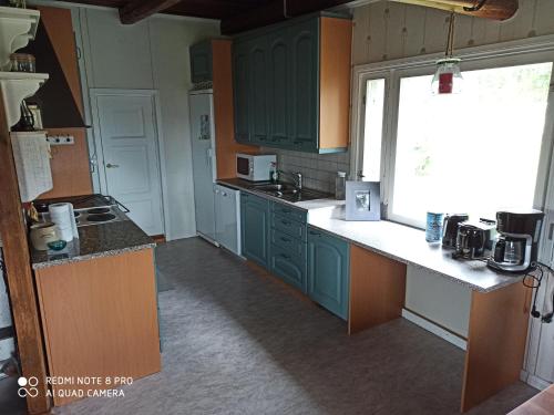 an empty kitchen with green cabinets and a window at Laukkumäki farm in Iisalmi