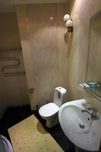 a bathroom with a white toilet and a sink at Alpen Ville in Almaty