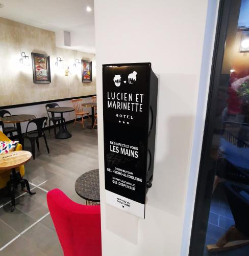 a sign on a wall in a restaurant with chairs at Hôtel Lucien & Marinette in Paris