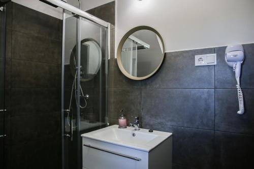 a bathroom with a sink and a shower with a mirror at Balkon Apartmanház Panzió in Balatonfüred