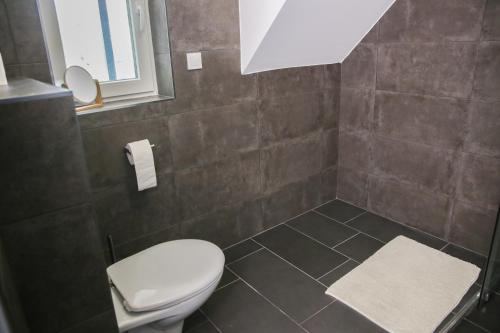 a bathroom with a toilet and a tiled floor at Balkon Apartmanház Panzió in Balatonfüred