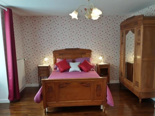 1 dormitorio con cama de madera y almohadas rojas en Chambres d'Hôtes et Table d'Hôtes- Valentine 44, en Sainte-Mère-Église
