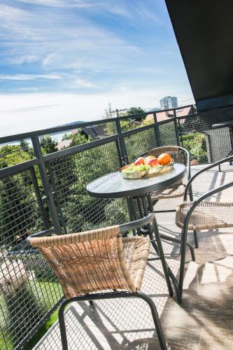 a table and chairs on a balcony with a plate of fruit at Balkon Apartmanház Panzió in Balatonfüred