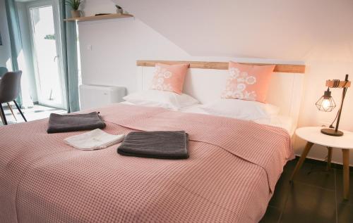 a bedroom with a bed with pink and white sheets at Balkon Apartmanház Panzió in Balatonfüred