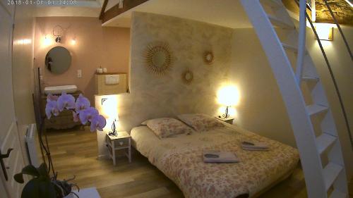 a bedroom with a bed and a spiral staircase at Gîte de La Pilotais in Pleslin-Trigavou