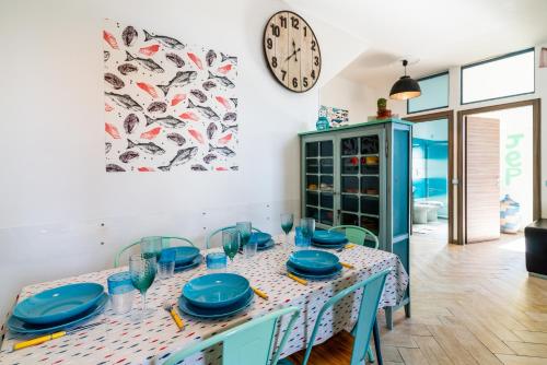 une salle à manger avec une table avec des plats bleus et une horloge dans l'établissement New Fishermans House Seaside, Air conditioning & WI-FI, à Bordighera