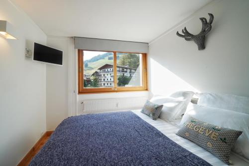 een slaapkamer met een groot bed en een raam bij La Ménandière in Megève