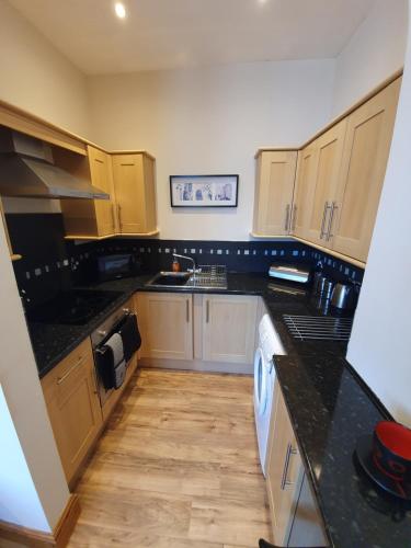 a kitchen with black counter tops and wooden cabinets at Marina Court LA14 2HL in Barrow in Furness