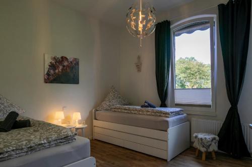 a bedroom with two beds and a window and a chandelier at HausAltenkamp in Bad Zwischenahn