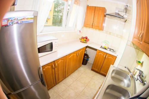 a kitchen with wooden cabinets and a stainless steel refrigerator at Apartament U Rybaka in Łeba