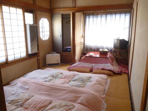 a large bed in a room with a window at Uotoshi Ryokan in Yamanouchi