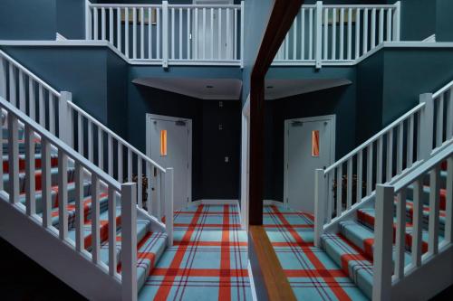 a hallway with three white doors with red and blue walls at The Dairy Hotel Queenstown, A Naumi Chapter in Queenstown