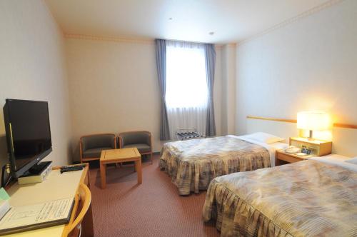 a hotel room with two beds and a television at Hotel Sapporo Sun Plaza in Sapporo