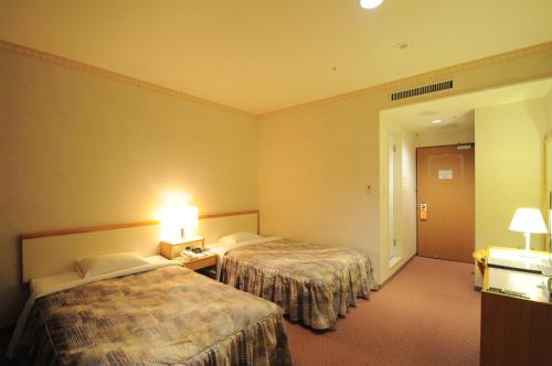 a hotel room with two beds and a hallway at Hotel Sapporo Sun Plaza in Sapporo