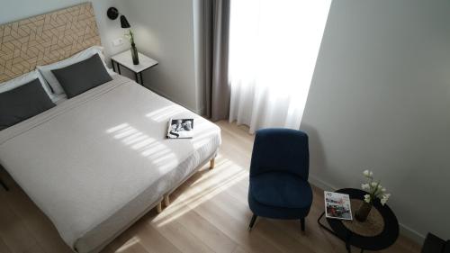 een slaapkamer met een bed en een blauwe stoel bij MD Design Hotel - Portal del Real in Valencia