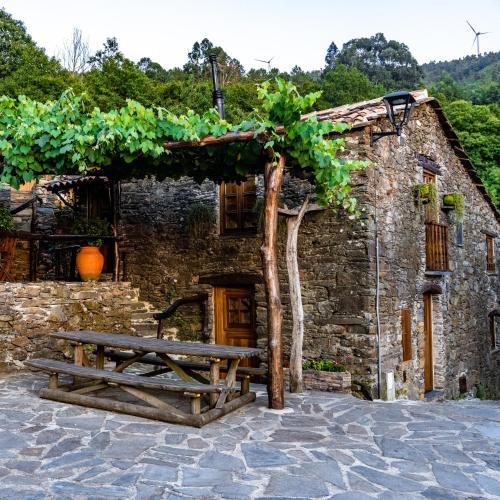 a stone building with a picnic table in front of it at Montanhas do Xisto - Casa da Eira in Candal