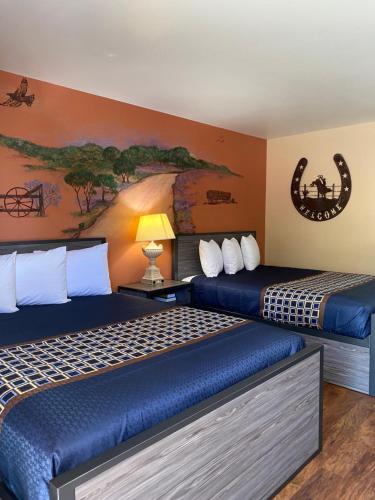 two beds in a room with a painting on the wall at Americas Best Value Inn - Legend's Inn in Junction