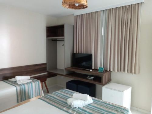 une chambre d'hôtel avec un lit et une télévision dans l'établissement Dunas de Marape, à Jequiá da Praia