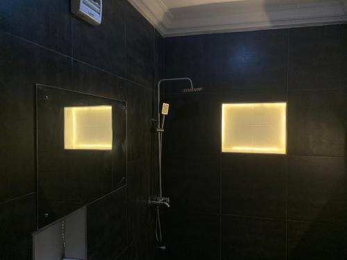a bathroom with a shower and two windows with lights at SS Suites in Abuja