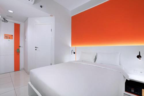a bedroom with a white bed and an orange wall at Starlet Hotel Jakarta Airport in Tangerang