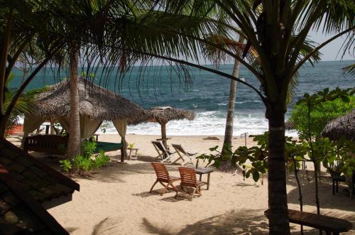 a beach with chairs and umbrellas and the ocean at Ibisbird Beach Bungalows, Sport, Spa and Restaurant in Tangalle