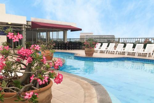 a swimming pool with chairs and flowers on a building at Piyada Residence Pattaya in Pattaya South