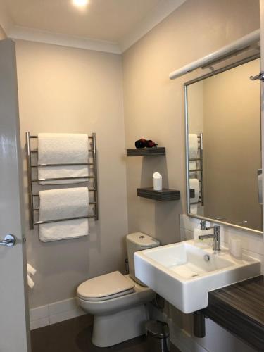 uma casa de banho com um lavatório, um WC e um espelho. em Saltair Luxury Accommodation - Adults Only em Albany