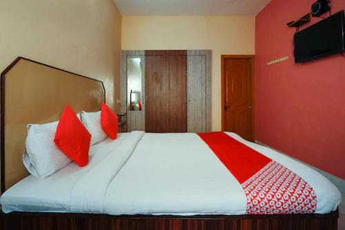 a bedroom with a bed with red and white pillows at Jaya Krishna Mansions in Vellore