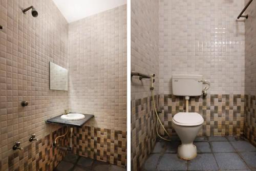 a bathroom with a toilet and a tiled wall at Jaya Krishna Mansions in Vellore