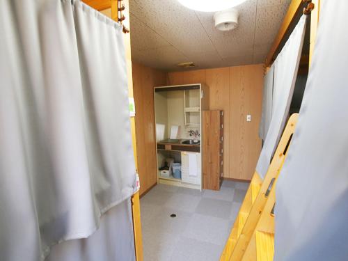 a room with a white curtain and a kitchen at Hostel J Culture168 in Toyonaka