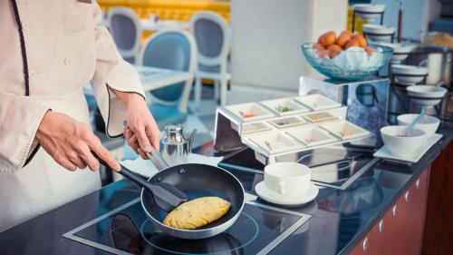 a person cooking food in a pan on a counter at Dorsett Shanghai in Shanghai