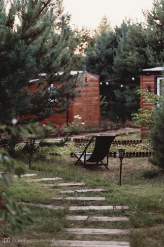 a chair sitting on the grass in a yard at Miodowy Zakątek Całoroczne Domki i Pokoje przy Suntago, Deepspot, Pyszne Śniadania, Grill in Mszczonów