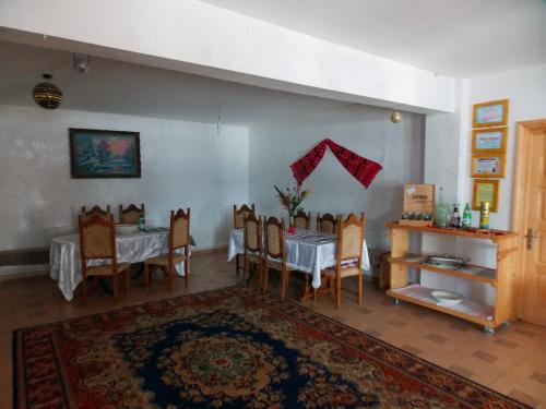 a dining room with a table and chairs and a rug at Pensiunea Paradiso in Poiana Teiului