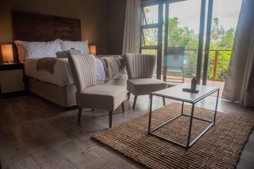 a bedroom with a bed and a chair and a table at Forest Hill Wilderness in Wilderness