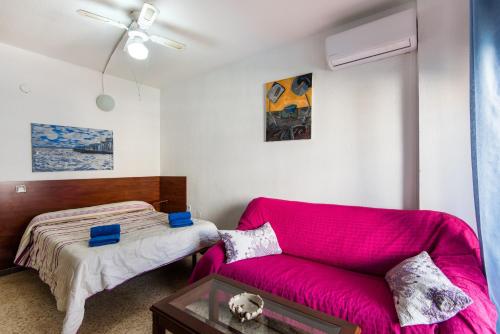 un soggiorno con divano rosa e letto di Apartamento Pino Torremolinos a Torremolinos