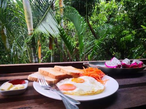 a plate of food with eggs and bread on a table at Hot Coffee Guest House and Resort in Ban Mae Na Chon