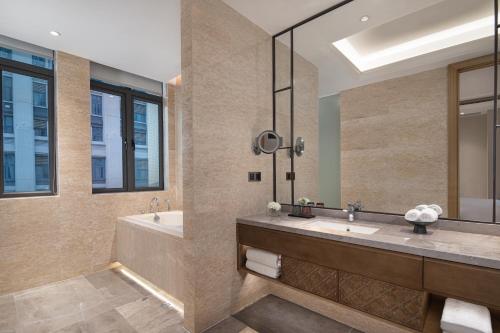 a bathroom with two sinks and a tub and a mirror at C&D Hotel,Xiamen Xiang'an-Late Check Out & Free Welcome Snacks in Xiamen