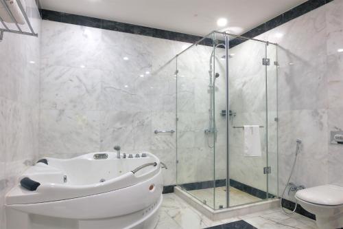 a bathroom with a shower and a tub and a toilet at The Proud Hotel Al Khobar in Al Khobar