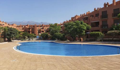 una gran piscina azul frente a algunos edificios en Romántico apartamento, piscina y BBQ en Playa La Tejita en El Médano